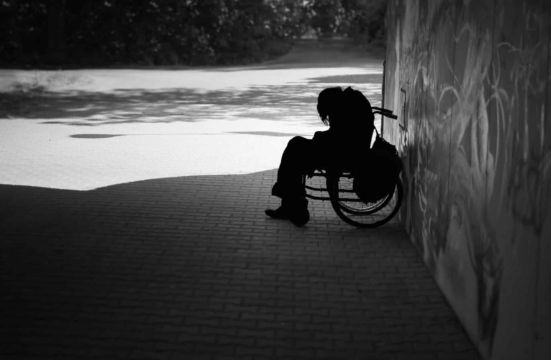 Person sitting in wheelchair under tunnel in black and white