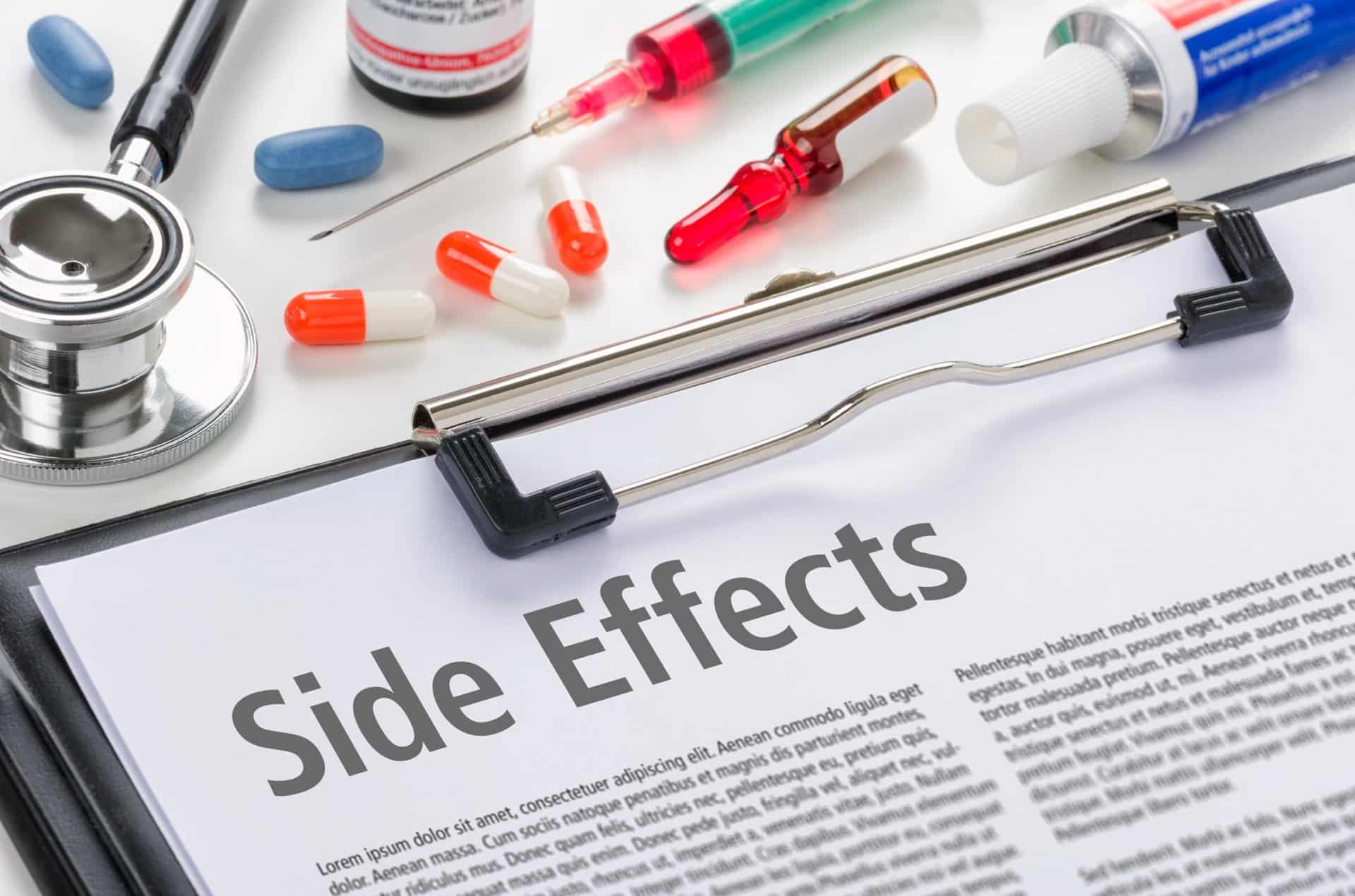 The text Side Effects written on a blipboard next to needles and medication