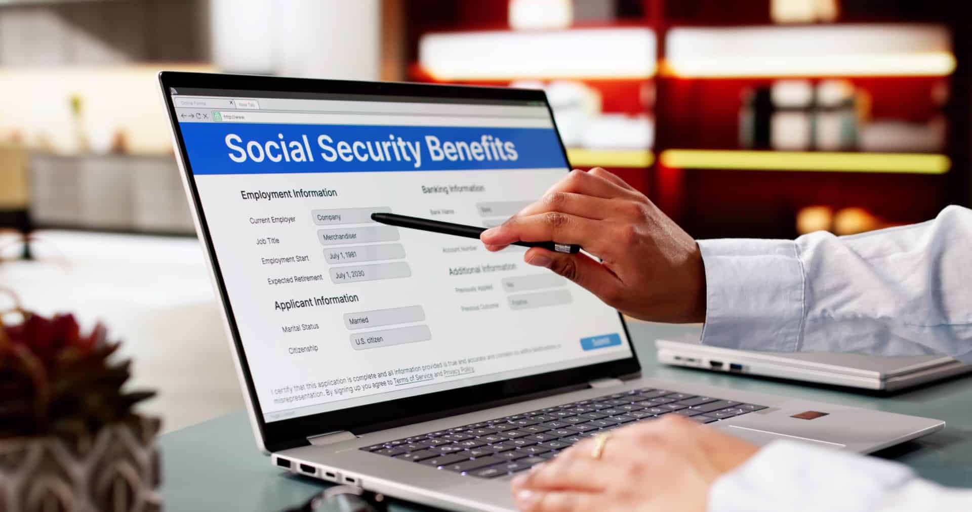 A person using a pen to point at a computer screen that says Social Security Benefits
