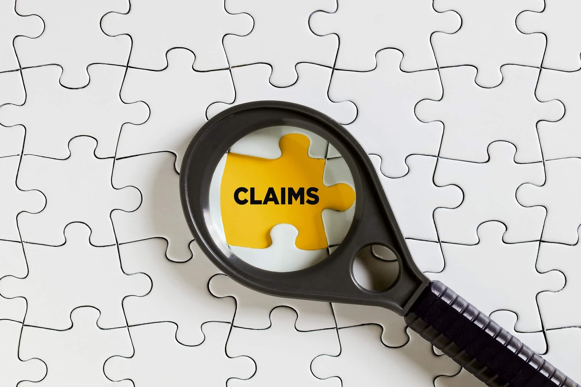 Magnifying glass focusing on a puzzle piece | Denied Disability Claims | Drew L Johnson, P.C.